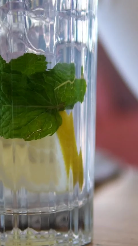 Pouring Water over Ice Cubes, Lemon Slices and Mint Making Lemonade Video stock 305980669