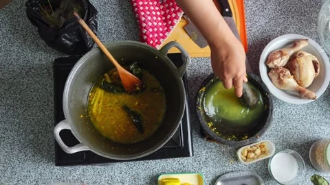 Pouring water into stone mortar to rinse out remaining spice paste before Stock Footage 344910756