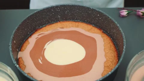 Pouring white liquid onto layered dessert in indoor kitchen Видео 342879646