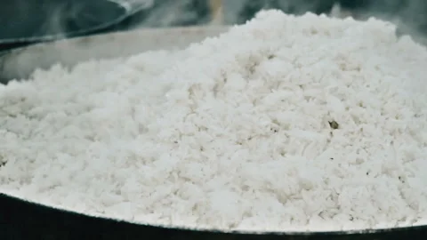 Pouring white long-grain rice into a frying pan for cooking or toasting Video stock 339078723