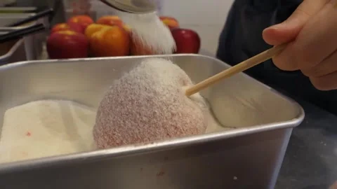 Pouring white sugar over a fresh apple on a wooden stick close-up Stock Footage 345292757