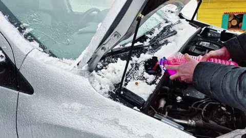Pouring windshield washer fluid into car engine in winter Stock Footage 325994160