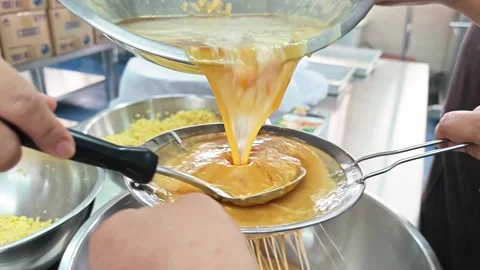 Pouring yellow egg batter through a metal strainer. Stock Footage 346536944