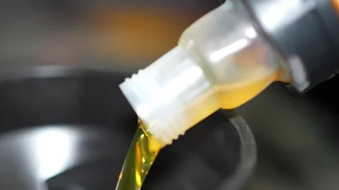 Pouring Yellow Liquid into Black Container Under Bright Light Stock Footage 346119869