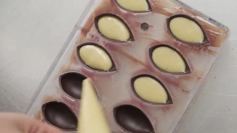 Pouring yellow mango passion fruit filler into molded chocolate with pastry c Stock Footage 132800274