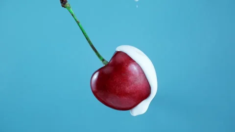 Pouring yoghurt from the top over a cherry in Slow Motion 1000fps Stockbeeldmateriaal 330533126