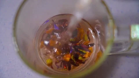 Pours boiling water into a cup for brewing fruit tea. Video stock 321687657