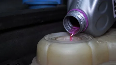 Pours red antifreeze into the car Stock Footage 139747185