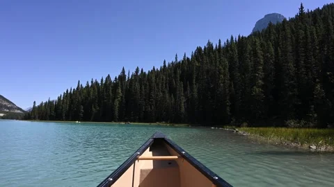 POV action from a canoe as it is paddled close to shore on a mountain lake that Stock Footage 340240195