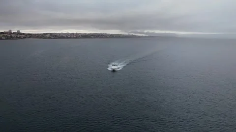 POV aerial drone view tracking a speeding yacht on a bay during a cloudy day Stock Footage 246085245