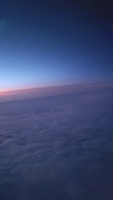 POV air plane window view flying above fluffy clouds at pink sunset horizon. Stock Footage 340359833