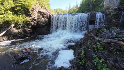 POV approach over slick rocks toward waterfall from abandoned dam in Quebec. Video stock 344464291