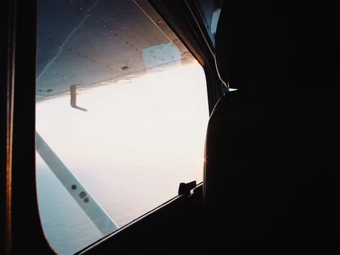 POV from backseat of small plane looking out window over ocean at sunrise Stock Footage 75917761