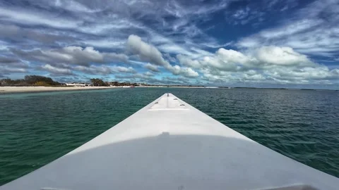 POV boat bow navigating crystal clear turquoise water toward a tropical beach Stock Footage 345177963