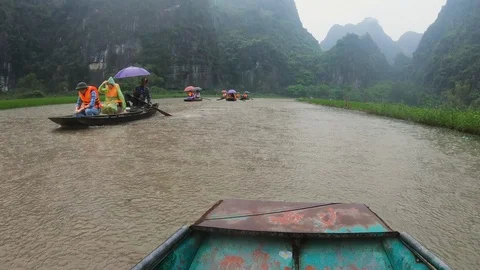 POV from boat floating on river passing by tourists during rainstorm, Ninh Binh Stock Footage 147354089