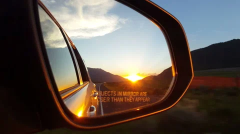 POV - Briliant sunset in mountain pass in auto rearview mirror while driving Stock Footage