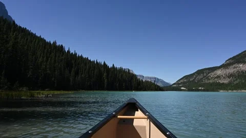 POV from a canoe while paddling on a mountain lake with a clear blue sky. Stock Footage 340240192
