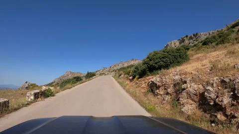 POV car driving on straight two way old asphalt road through a mountain in Spain Stock Footage 165657232