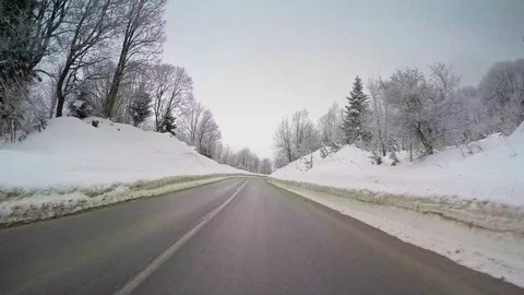POV car travel winter scenery mountain snow forest vehicle drive wet curvy road Stock Footage