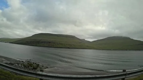 POV car window shot driving past a rocky beach and green mountains, Faroe Island Stock Footage 337534994