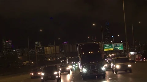 POV Cars and trucks on multiple lane highway over lit skyscraper Chicago skyline Stock Footage