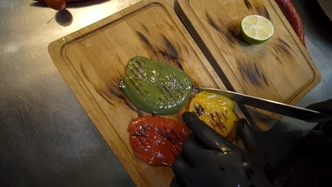 POV chef hands cutting fried pepper on a wooden plank Video stock 105271985