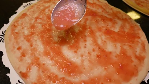 POV (close-up): Man putting tomato sauce on a pizza with a spoon (slow zoom out) Stock Footage 336761287