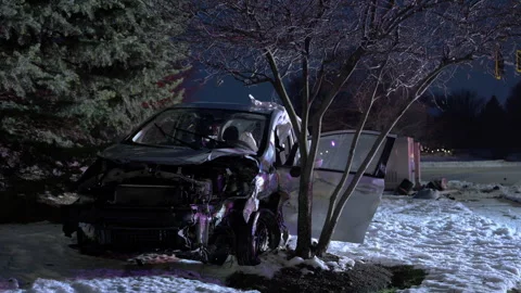 POV Close up. Nighttime scene of a damaged car after a crash, resting on a snowy Stock Footage 324759652