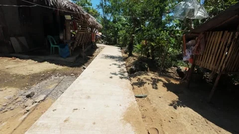 POV of concrete path winds through a village with thatched roofs. Vídeos de archivo 334626978