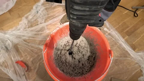 Pov Construction worker mixing cement in an orange bucket using a powerful drill Stock-Footage 314083427