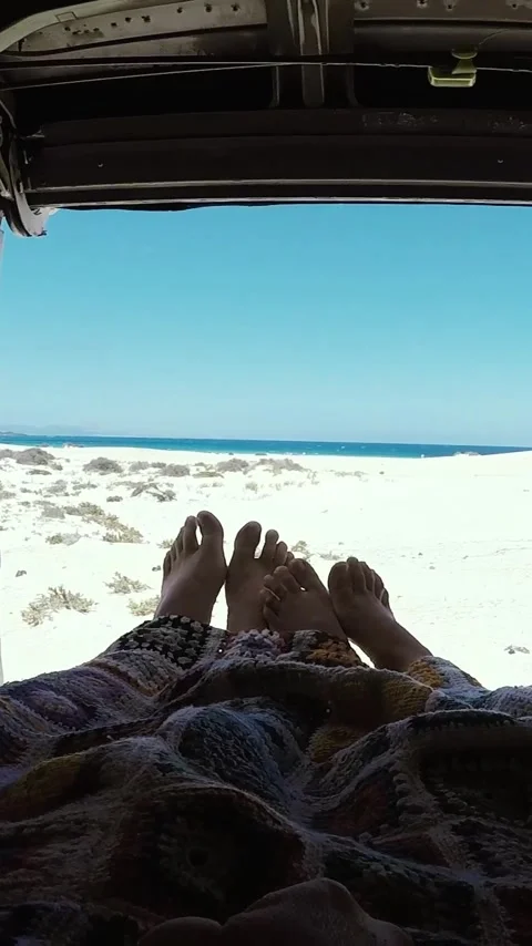 Pov of a couple's feet resting under a blanket inside a campervan, looking out Stock Footage 344815957