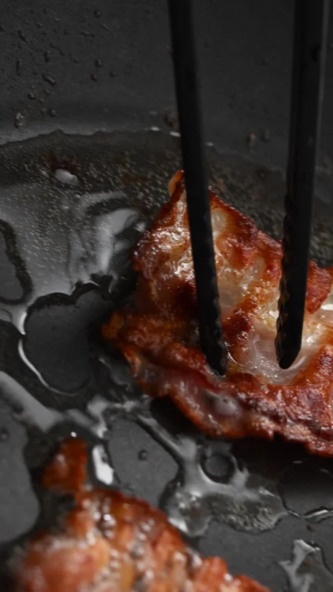POV: Crispy bacon sizzling in a pan, close-up shot. 動画素材 319494277