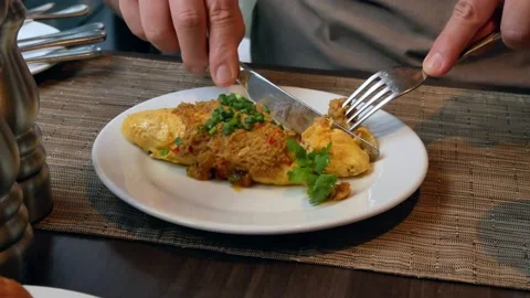 POV to the dish of omelette while a man using fork and knife to cut it Stock Footage 151624107