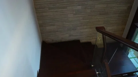 POV Doing Down Dark Brown Wooden Staircase With Glass Railing. Follow Shot Stock Footage 154256323