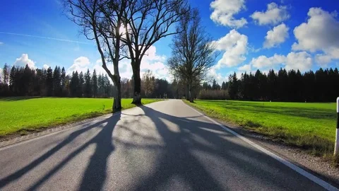 POV drive countryside narrow road green grassland shining sun car travel gopro Stock Footage