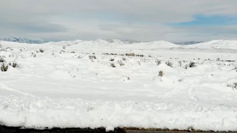 POV-Drive Plate side-Passing snow covered sagebrush plain Patches of blue sky Stock-Footage 99479528