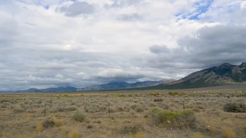 POV-Drive Plate-side view-Sagebrush flat Gray clouds Shadow mountain Stock-Footage 97242803