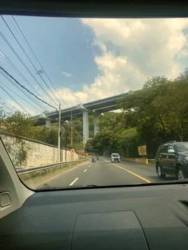 POV Drive Under Elevated Highway Structure Against Blue Sky Stock Photos