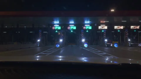 POV of a driver passing through a toll booth on a toll road at night. You drive Stock Footage 309016845