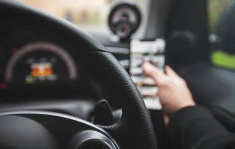 POV Driver on the phone whilst at the wheel of a car, texting and driving. Stock Photos