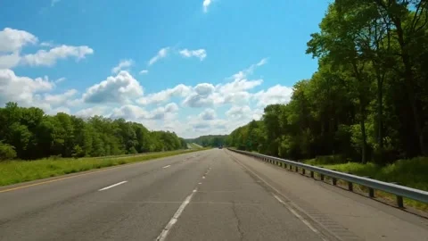 Pov driving down an open multi lane highway surrounded by green forest Stock Footage 342943323