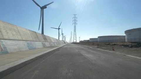 POV: Driving Down a Seaside Road Wind Turbines and Pylons Stock Footage 203876068