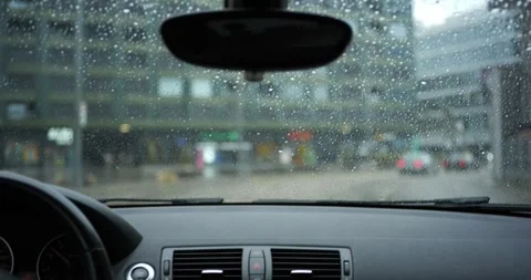 POV driving inside car on rainy city street with rain droplets on windshield Stock Footage 343506009