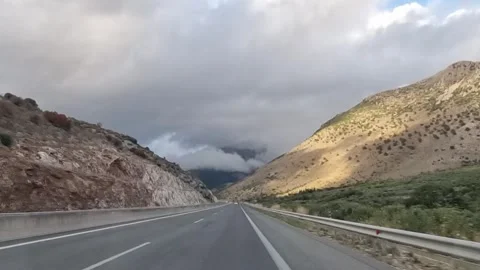 POV driving on mountain highway with dramatic cloudy sky Stock Footage 318305638