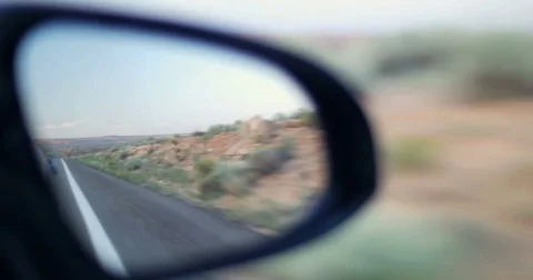 POV driving moving by red desert side car rear view mirror reflection 4K Stock Footage 78043146