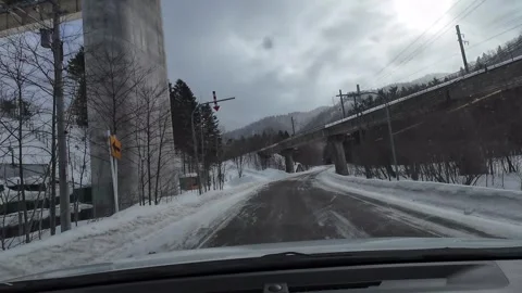POV Driving Under Highway Overpass on Snowy Road Furano Hokkaido Japan Stock Footage 333587743