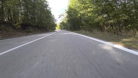 POV fast driving through mountain pass with curvy roads under tree shadows Stock Footage