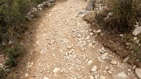 Pov first person view going down a steep path of rocks and dirt between bushes 库存影片 164612471