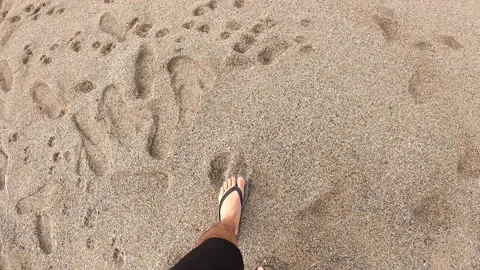 POV first person view walking on wet sand looking down the beach with sandals on Video stock 194444697