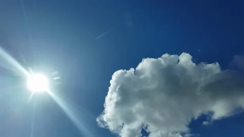 POV flying under some tiny clouds with the sun shining in a deep blue sky Stock Footage 300605508